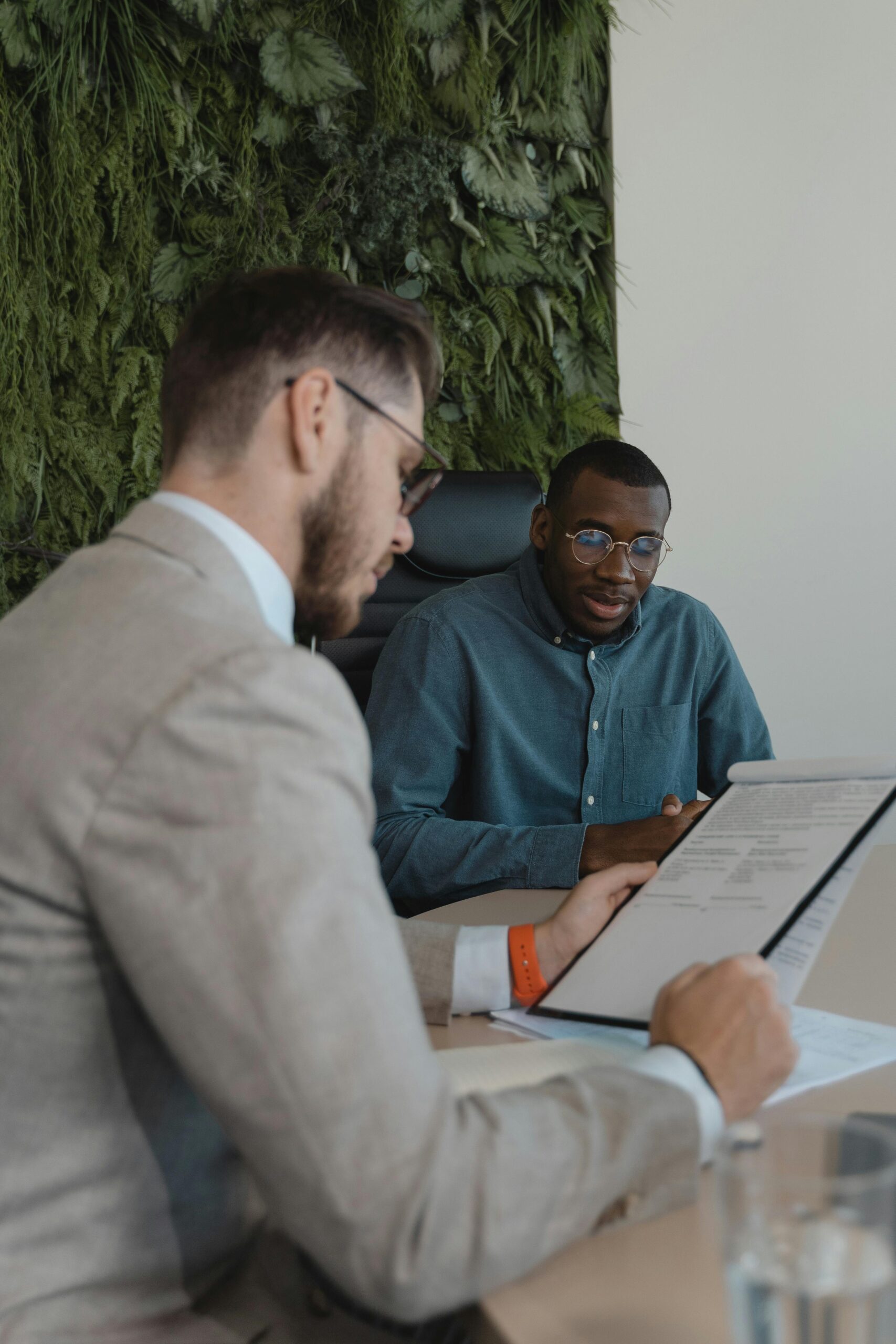 Two men in a modern office setting discussing a document during a business meeting.