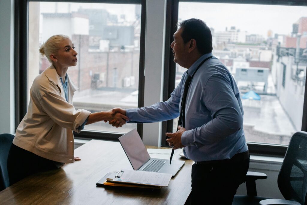 Professional handshake between two colleagues in a modern office setting.